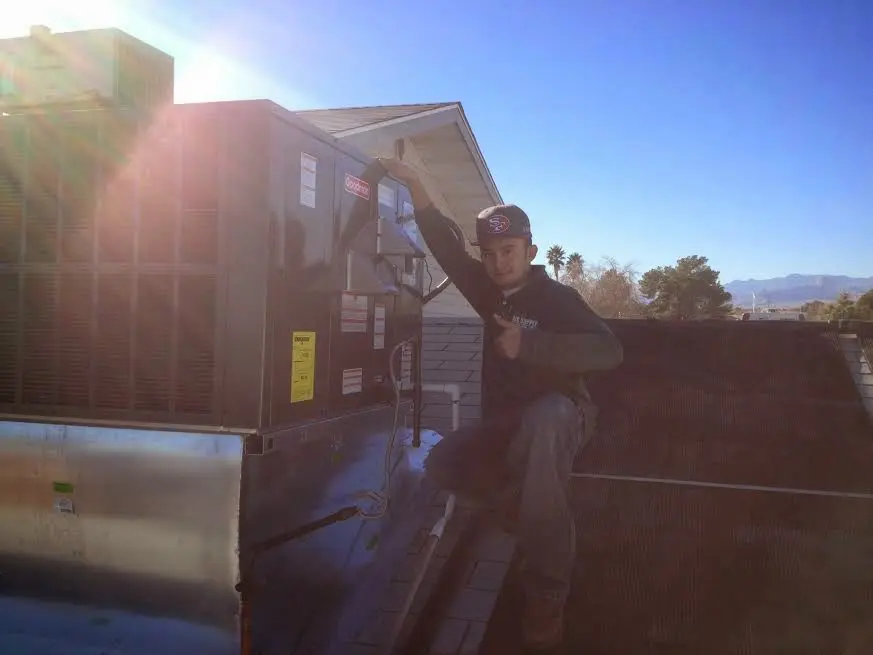 HVAC technician performing AC Tune-Up on a rooftop unit in Roma